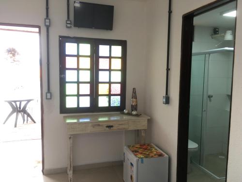 a bathroom with a table and a window and a television at Pousada Brisa e Mar in Praia do Frances