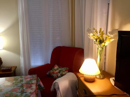 - un salon avec une chaise rouge et un vase de fleurs dans l'établissement Casa Rural Francisco Pizarro, à Herrera del Duque