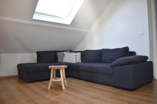 a blue couch in a living room with a stool at familieverblijf De groene Specht in Sluis