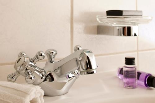 a bathroom sink with a faucet and a bottle of soap at Lodner Hotel Drei Mohren in Lauingen