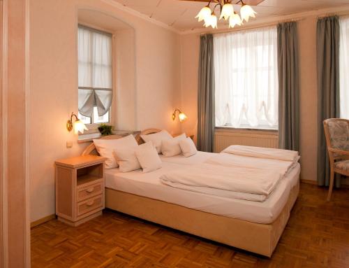 a bedroom with a large white bed and two windows at Lodner Hotel Drei Mohren in Lauingen