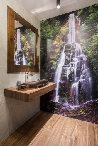 a bathroom with a waterfall mural on the wall at Sidharta Resort in Obarsia-Lotrului