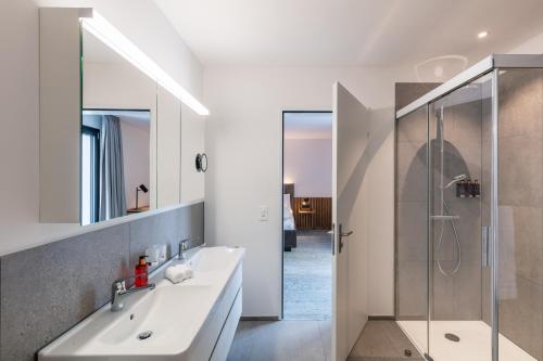 a white bathroom with a sink and a shower at Macardo Premium B&B in Bissegg