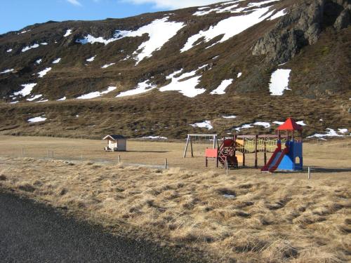 a playground in front of a snow covered mountain at Ásbrandsstadir Cottages in Vopnafjörður