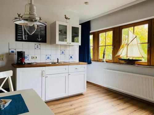 a kitchen with white cabinets and a sailboat on the wall at Kajüthus Apartment 1 in Fehmarn