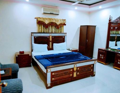 een slaapkamer met een groot bed met een houten hoofdeinde bij New Royal Residency PECHS in Karachi