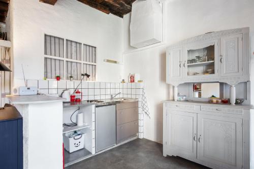 a white kitchen with white cabinets and appliances at Studio charmant à Villeneuve-lès-Avignon, 45m², balcon in Villeneuve-lès-Avignon