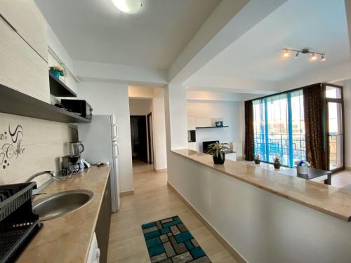 eine Küche mit einem Waschbecken und einem großen Fenster in der Unterkunft Apartament Ella T2 in Mamaia Nord – Năvodari