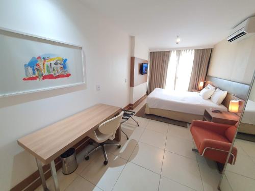 um quarto de hotel com uma cama, uma secretária e uma mesa em Athos Bulcão Executive By Rei dos Flats em Brasília