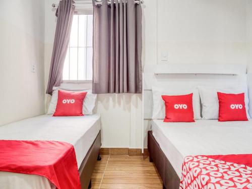 two beds in a room with red pillows at HOTEL PAULISTANO Terminal Tietê in São Paulo