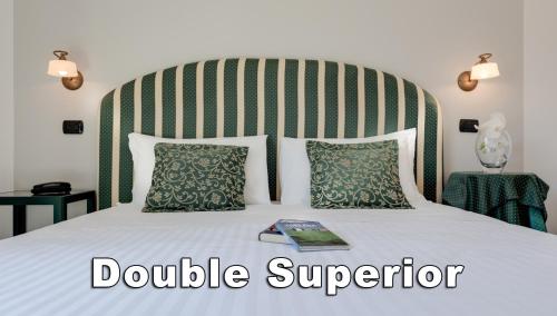 a bed with a large headboard and a book on it at Hotel Da Vinci in Montecatini Terme