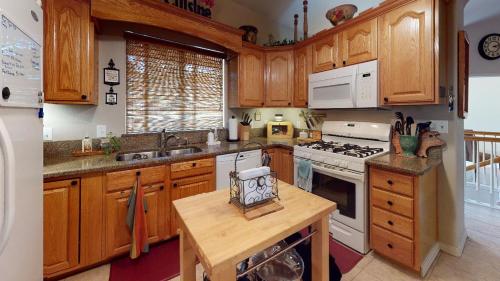 a kitchen with wooden cabinets and a white stove top oven at 120 Winding Meadow by Vacation Rentals for You in Monument