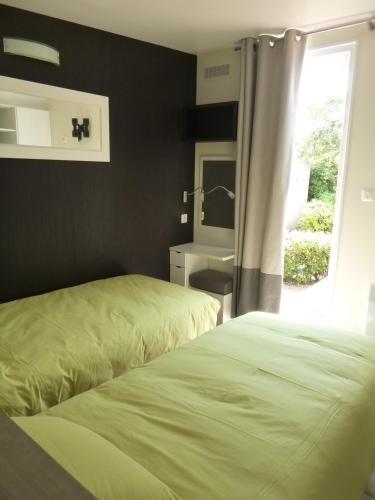 - 2 lits dans une chambre avec lavabo et miroir dans l'établissement Village vacances & camping de Gruissan, à Gruissan