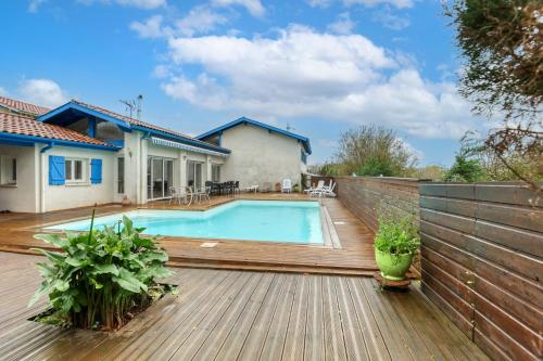 une cour arrière avec une piscine et une terrasse en bois dans l'établissement Villa spacieuse à Bidart avec piscine privée 330 m², à Bidart