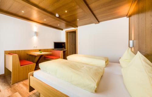 a bedroom with two beds and a desk and a table at Tyroler Hof in Grän