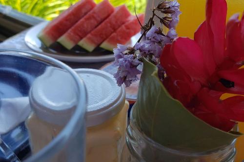 un jarrón con una flor y un plato de fruta en Elephant GuestHouse Beira Mar - Suítes com Café da Manhã en Ilhabela