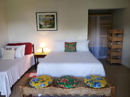 a bedroom with two beds and a table with a lamp at Elephant GuestHouse Beira Mar - Suítes com Café da Manhã in Ilhabela