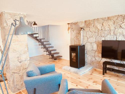 a living room with a stone fireplace and a tv at Mountain Chalet in Covilhã