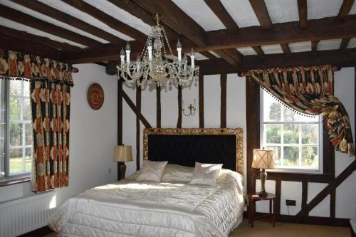 a bedroom with a large bed and a chandelier at Holmbush House in Hellingly