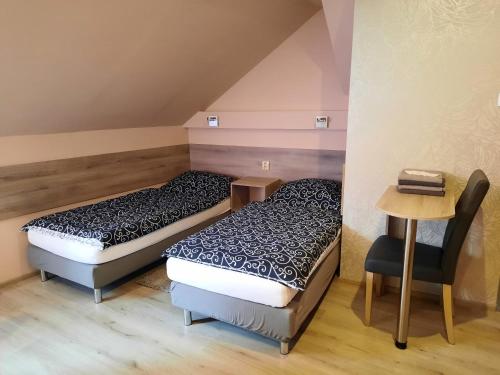 two beds in a room with a table and a chair at Penzion Avena in Stříbro