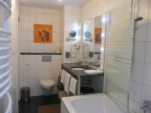 uma casa de banho com uma banheira, um lavatório e um WC. em City Hotel em Ludwigsburg