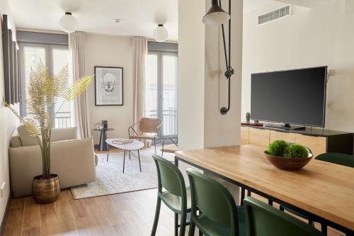 uma sala de estar com uma mesa com cadeiras e uma televisão em Sonder Malasaña em Madrid