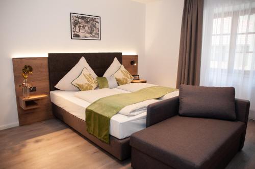 a bedroom with a bed and a chair at Gasthaus Stöttnerbräu in Vohburg an der Donau
