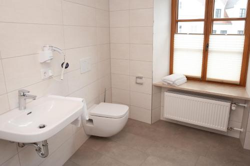 a white bathroom with a toilet and a sink at Gasthaus Stöttnerbräu in Vohburg an der Donau