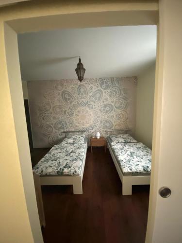 ヘルツォーゲンラートにあるcasa mediterraneaのベッド2台が備わる壁紙の客室です。