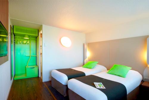 レンヌにあるカンパニール レンヌ ウェスト クルーネのベッド2台(緑の枕付)が備わる客室です。