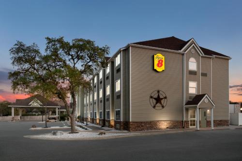 een groot gebouw met een bord aan de zijkant bij Super 8 by Wyndham San Antonio Airport North in San Antonio