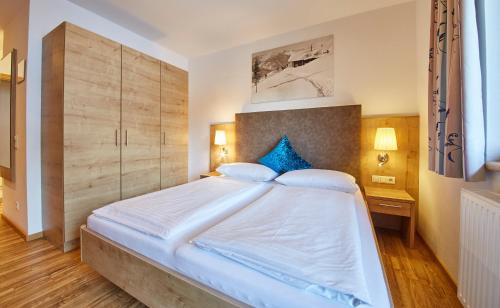 a bedroom with a large white bed with blue pillows at Johanneshof - Dein MOUNTAIN Wohlfühlhotel in Saalbach Hinterglemm