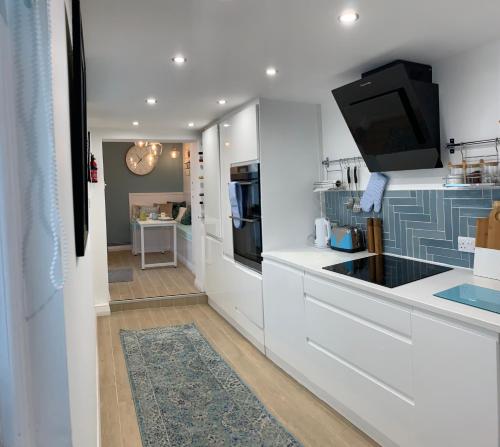 eine Küche mit weißen Schränken und einem Flachbildfernseher in der Unterkunft Blue Haven in Brighton & Hove