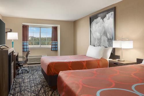 a hotel room with two beds and a flat screen tv at Super 8 by Wyndham San Antonio Airport North in San Antonio