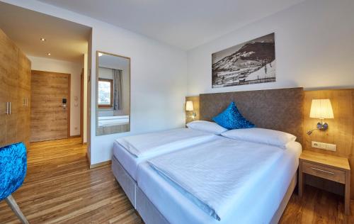 a bedroom with a large bed with blue pillows at Johanneshof - Dein MOUNTAIN Wohlfühlhotel in Saalbach Hinterglemm