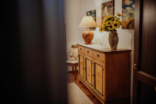 eine Vase mit Blumen auf einem Schrank mit einer Lampe darauf in der Unterkunft Residenza Golfo Degli Ulivi in Caprioli