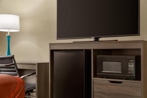 a tv on top of a entertainment center with a microwave at Super 8 by Wyndham San Antonio Airport North in San Antonio