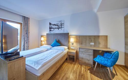 a bedroom with a bed and a desk and a television at Johanneshof - Dein MOUNTAIN Wohlfühlhotel in Saalbach Hinterglemm