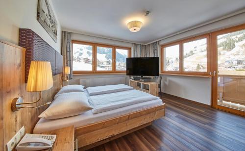 a bedroom with a bed and a flat screen tv at Johanneshof - Dein MOUNTAIN Wohlfühlhotel in Saalbach Hinterglemm