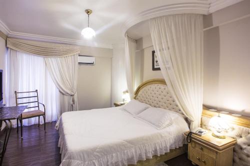um quarto com uma cama branca com cortinas e uma mesa em Hotel Lang Palace em Chapecó