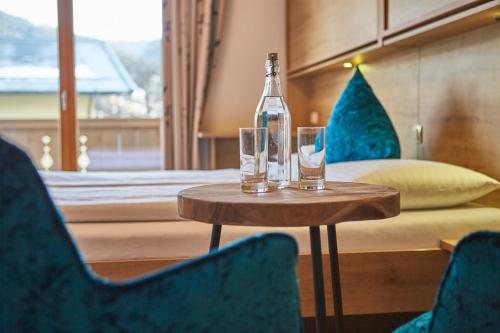 a bottle and two glasses on a table in a room at Johanneshof - Dein MOUNTAIN Wohlfühlhotel in Saalbach Hinterglemm