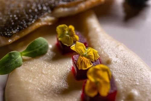 a close up of a dessert with yellow flowers on it at Anteliz Suites in Fira