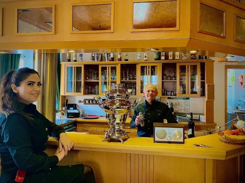 a man and a woman sitting at a bar with a trophy at Meister BÄR HOTEL Ostbayern in Floß