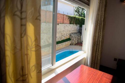 uma janela com vista para uma piscina exterior em Room in Apartment - You will relax with the amenities offered by this Standard Suite em Kigali