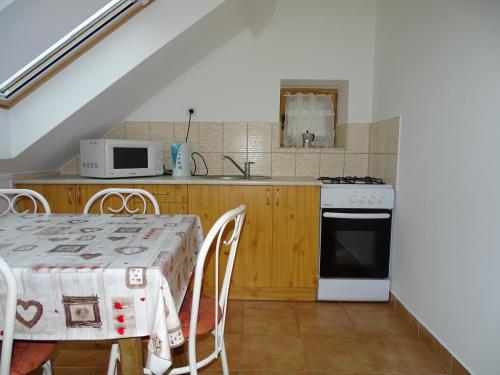 a kitchen with a table and a stove and a microwave at Vendvidék Kapuja Vendégház in Szentgotthárd