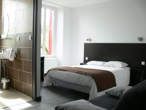 Saint-Julien-du-SaultにあるHotel Le Saint Julienのベッドルーム(大型ベッド1台付)、バスルームが備わります。