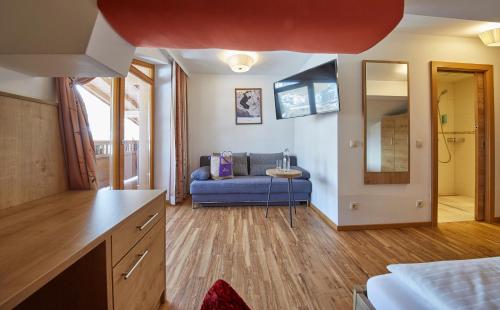 a living room with a blue couch and a mirror at Johanneshof - Dein MOUNTAIN Wohlfühlhotel in Saalbach Hinterglemm