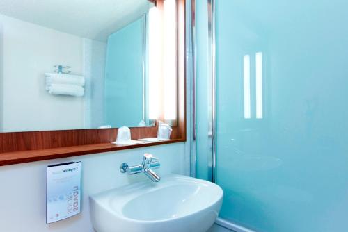 La salle de bains est pourvue d'un lavabo, d'un miroir et d'une douche. dans l'établissement Campanile Rennes Ouest Cleunay, à Rennes