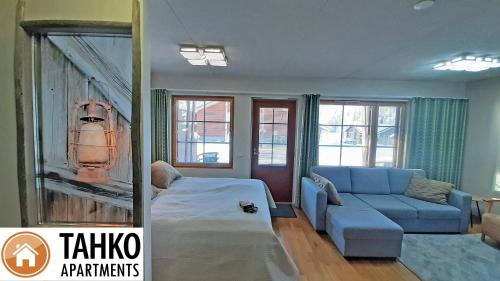 een woonkamer met een bank en een blauwe bank en ramen bij Apartments Tahko in Tahkovuori