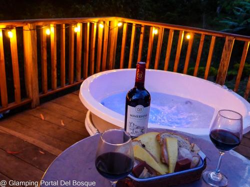 a bottle of wine and a bowl of food and two glasses at Glamping Portal Del Bosque in Pacho